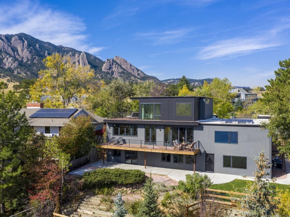 A completed custom home with three levels and a second-story deck with mountains in the background by Petra Custom Builders in Boulder County, CO