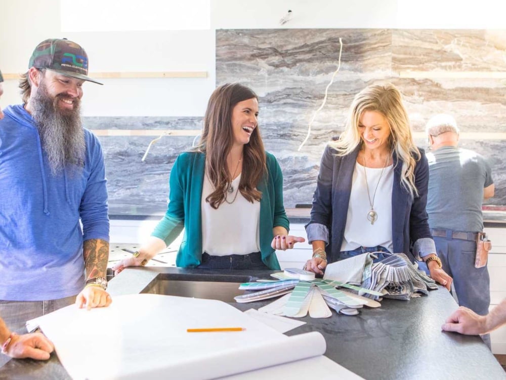 The Pack stands around a table with drawings and paint swatches, smiling and talking. Petra Custom Builders in Boulder County, CO. The Pack stands around a table with drawings and paint swatches, smiling and talking. Petra Custom Builders in Boulder County, CO.