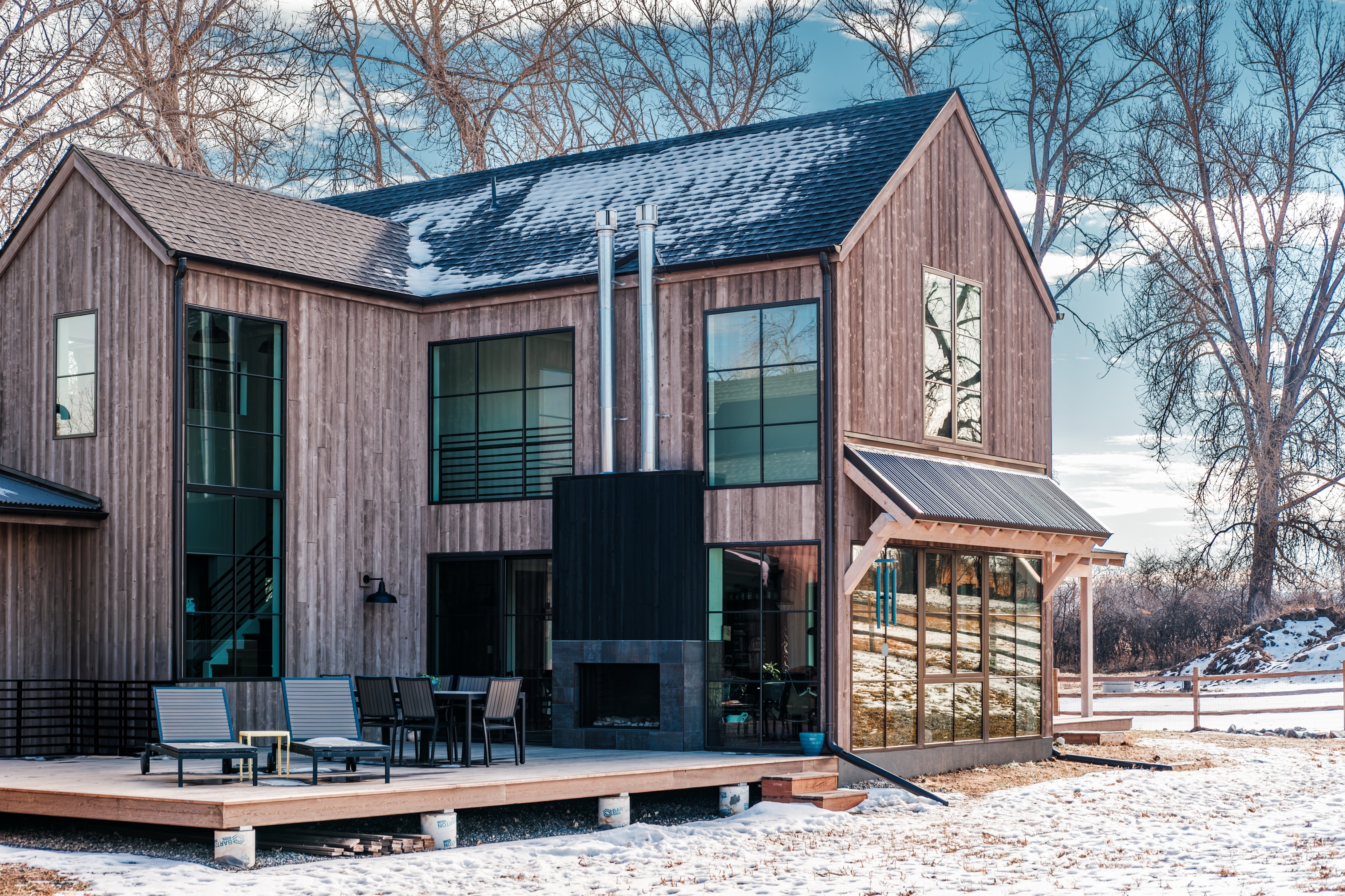 side view of a modern rustic home in winter with back porch