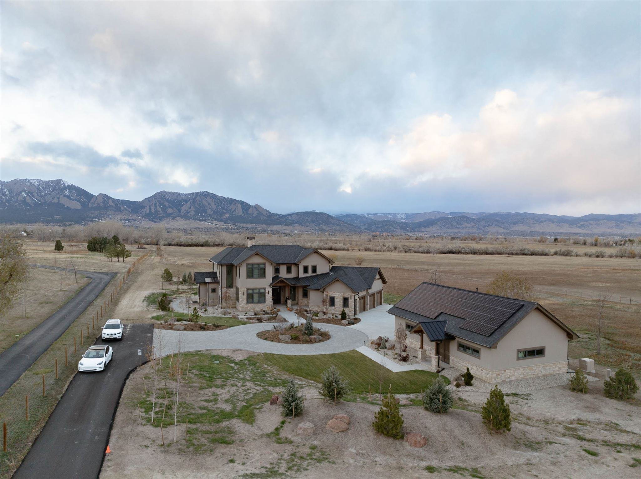 exterior shot of a custom built home in boulder colorado with two brown buildings on a large property with mountains in the background