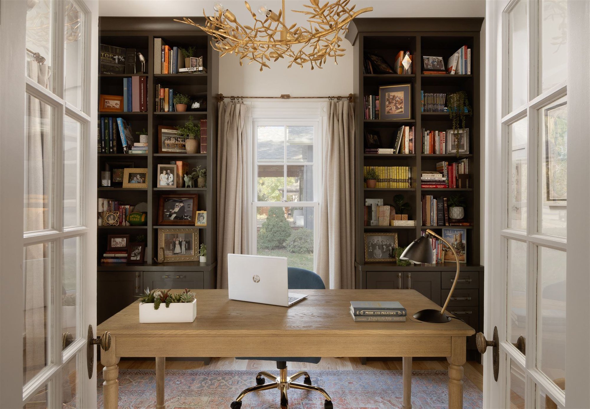 home office with dark green built-in bookshelves and white french doors