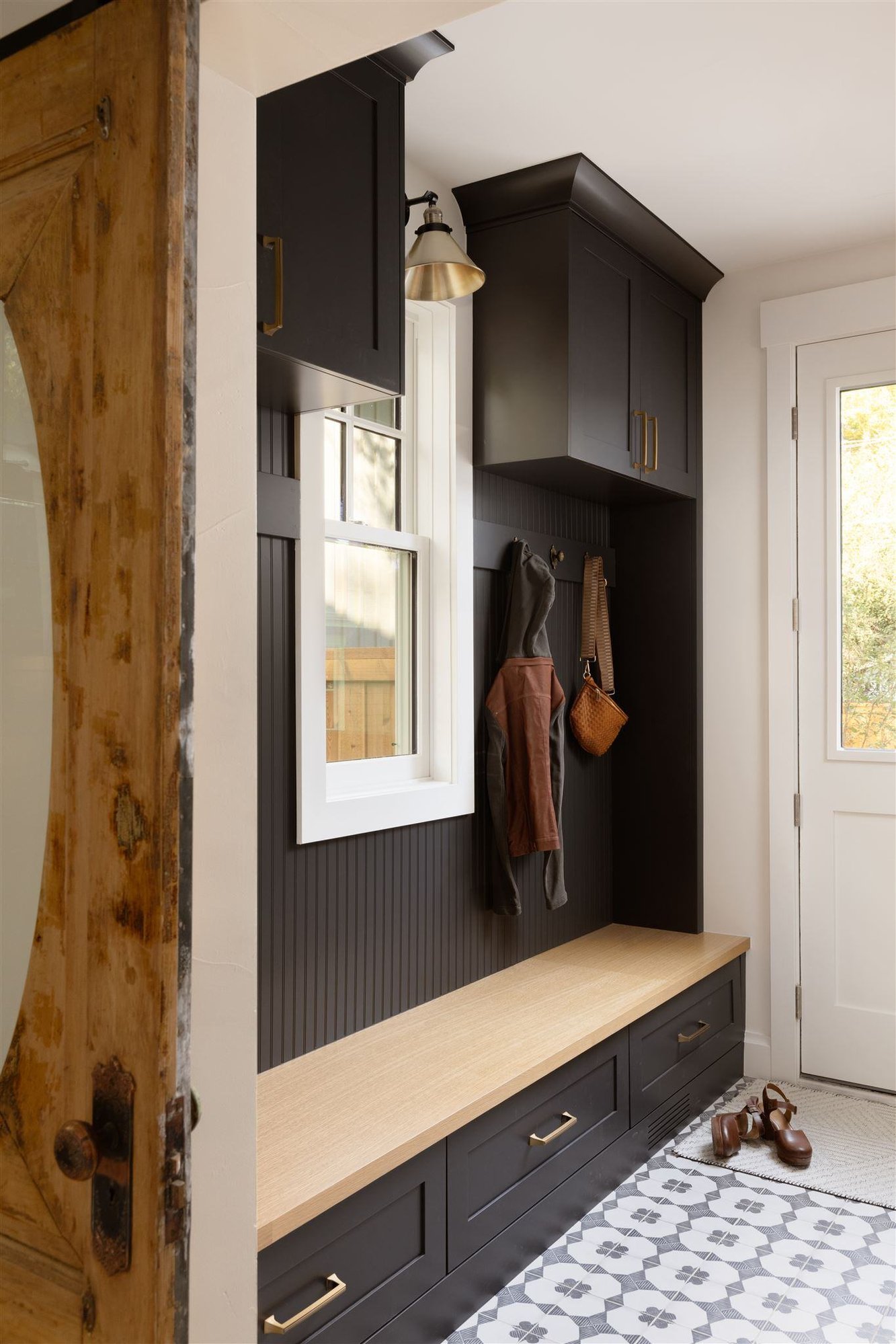 Mudroom with black cabinets and patterned floor tiles