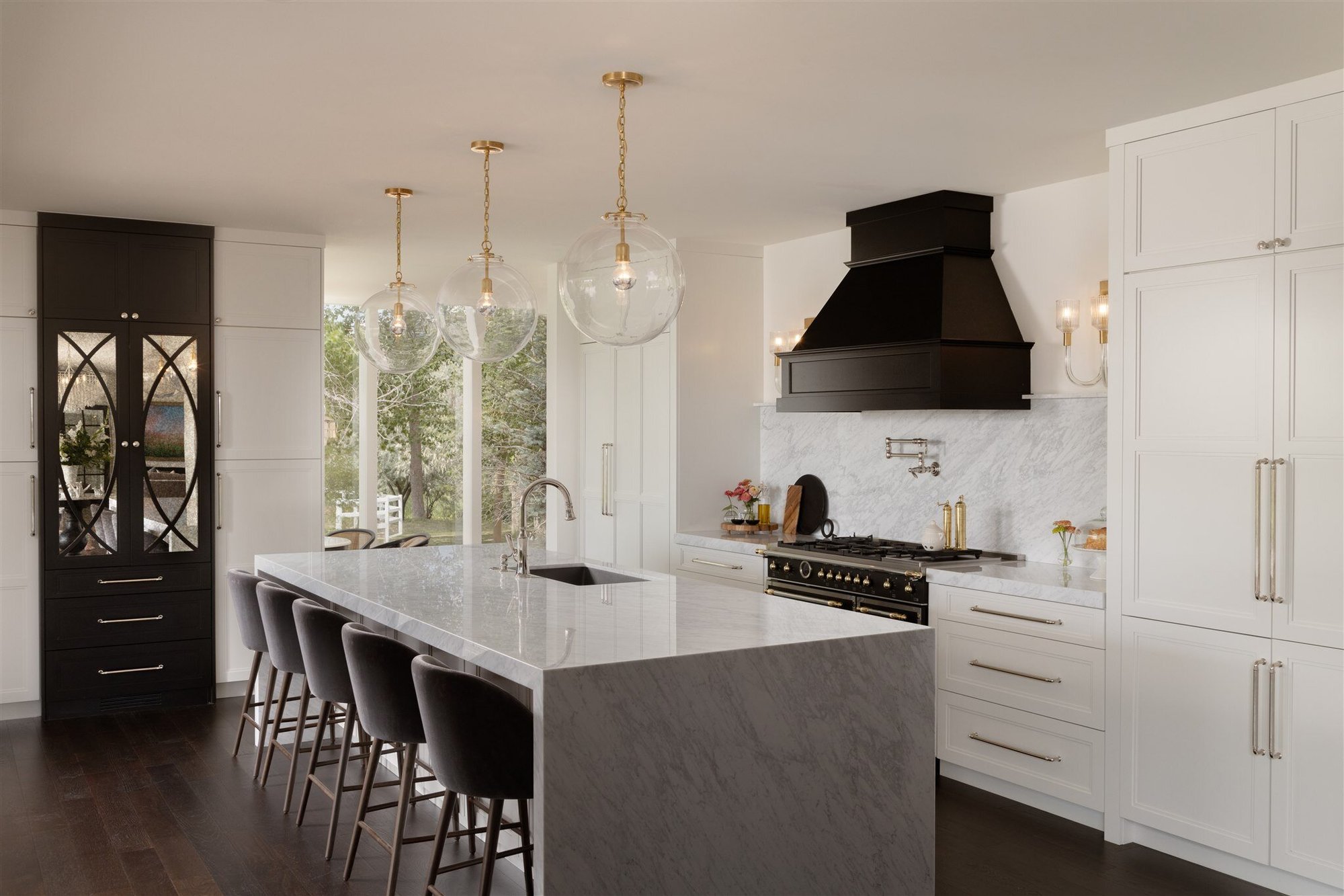 Luxury kitchen in Colorado with sleek kitchen island, white cabinets, a black kitchen hood, and custom lighting