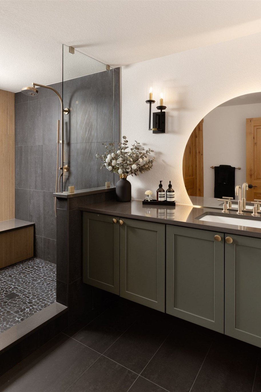 full bathroom remodel with dark tiles, floating vanity, and walk in shower with stone floor and large bench