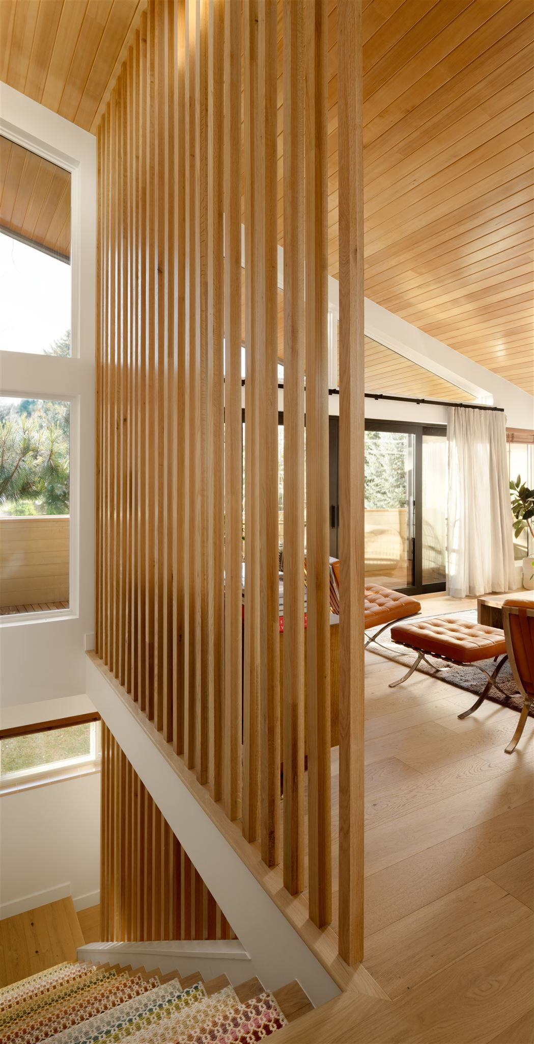 22 foot custom made slat wall that extends from lower level to upper level in remodeled midcentury home